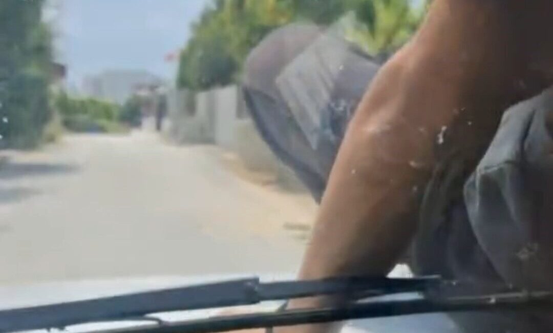 Adana’da bir kişinin otomobilin kaputunda yolculuk yapması görenleri hayrete düşürdü.