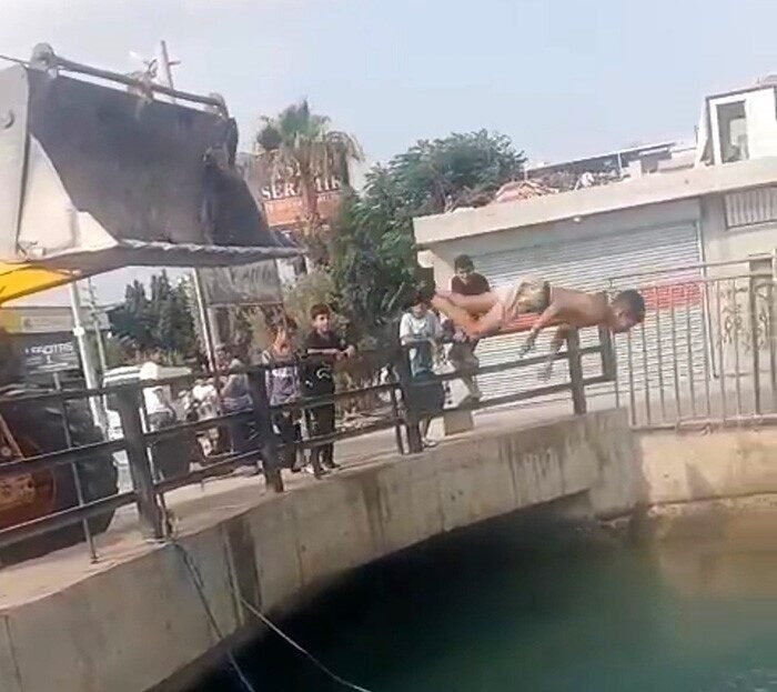 Adana’da bunaltan sıcakta serinlemek isteyen çocukların iş makinesine çıkıp sulama
