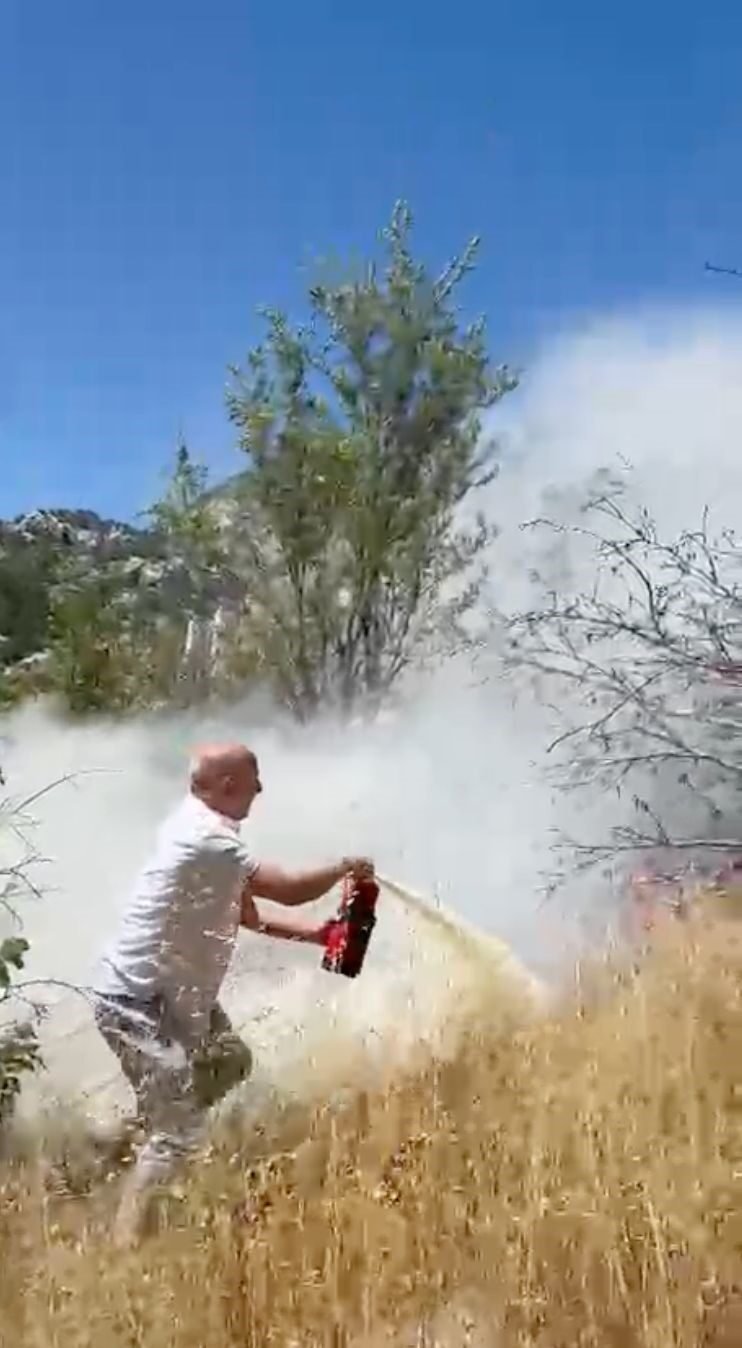 Yangını görüp aracındaki yangın tüpüyle muhtemel orman yangınının önüne geçti;