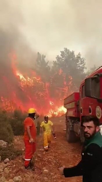 Antalya’nın Aksu ilçesinde yangınla mücadele eden ekipler, alevlerin arasında kalmaktan
